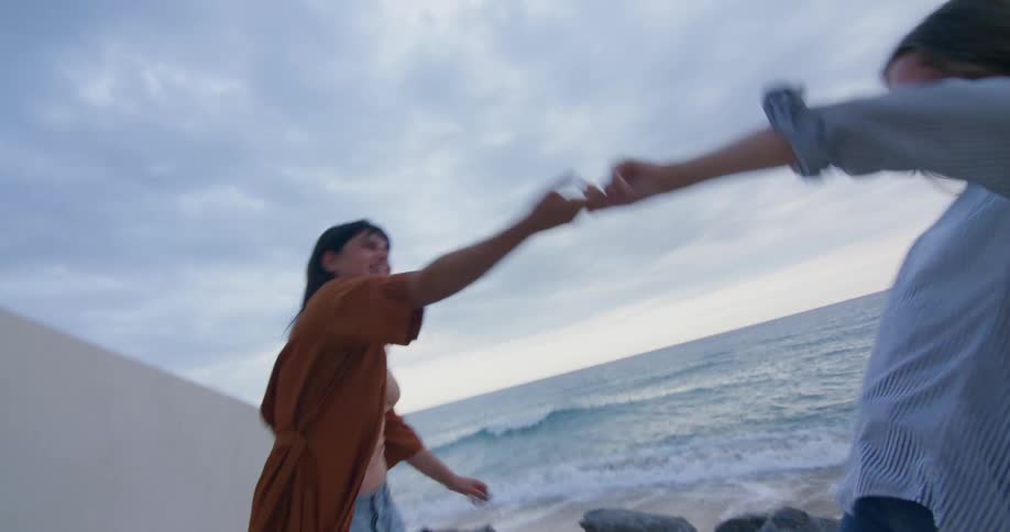 Happy couple running on a tunnel holding hands gets to a beach and hug
