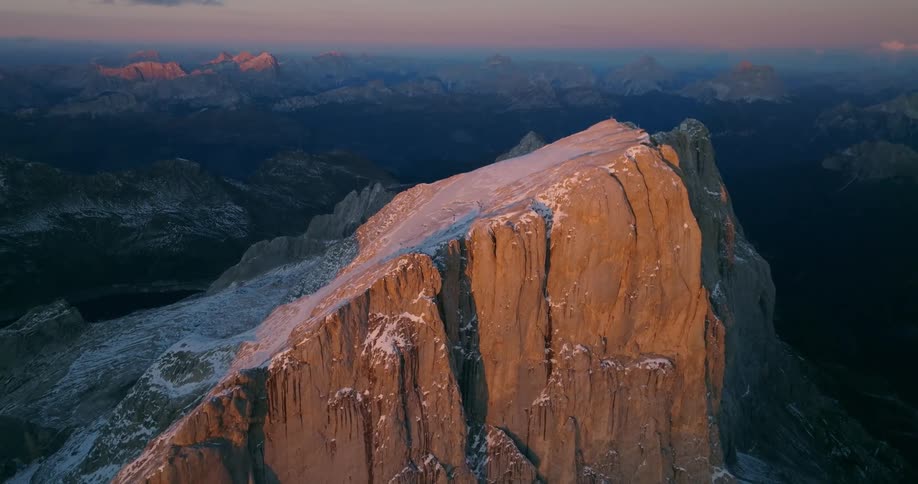 Snow covers plateau topping cliff bordered by river as fog covers mountain range
