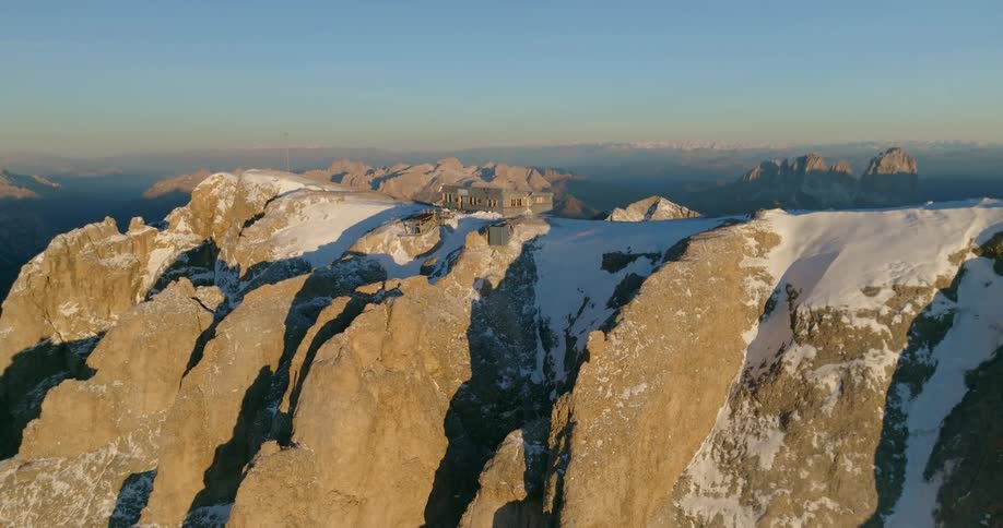 Aerial view of building on top of snowy mountain in mountainous region