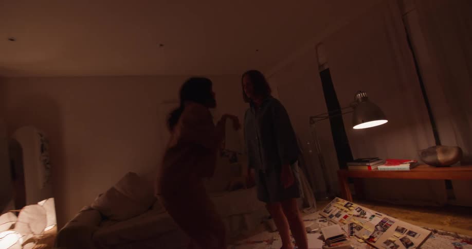 Women dance jump and enjoy themselves in living room at night