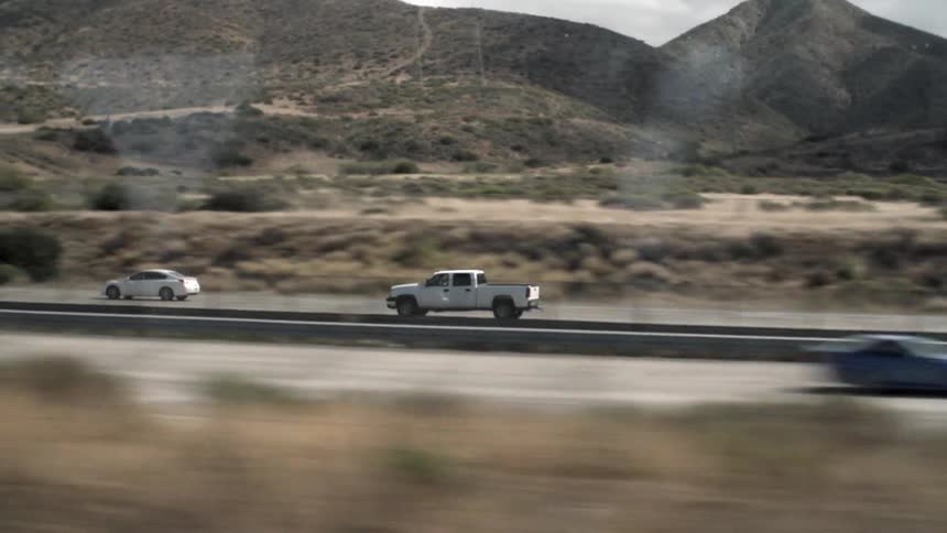 A white truck travels down a desert road