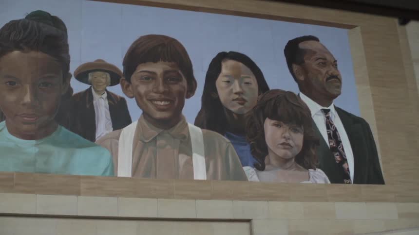 Man walking into city looking up at a mural on a building