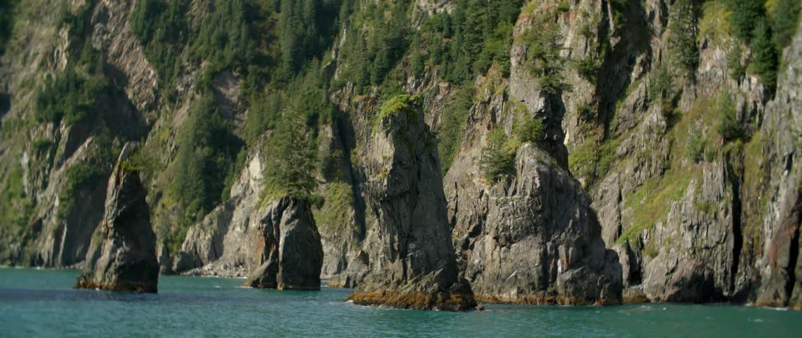 Waves crash below tall rocks along the coast