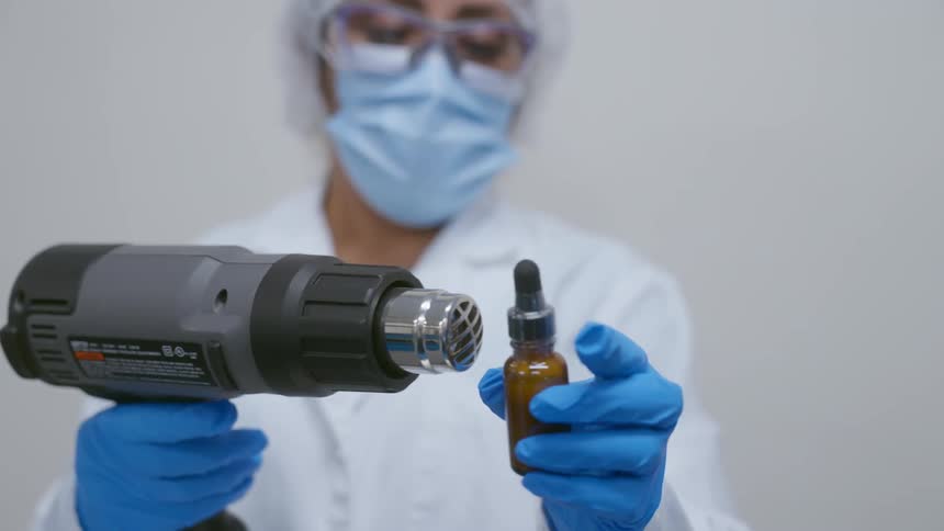 The scientist is sealing a bottle with a heat gun