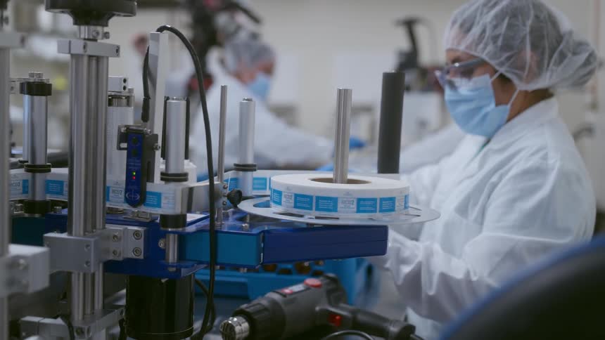 A factory worker removes plastic from an item