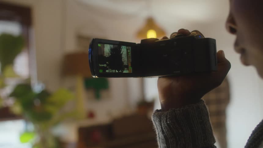 A young boy films inside his house as his dad walks out the door