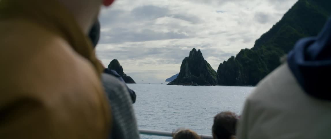 People on a ferry looking out at the water and rocky islands
