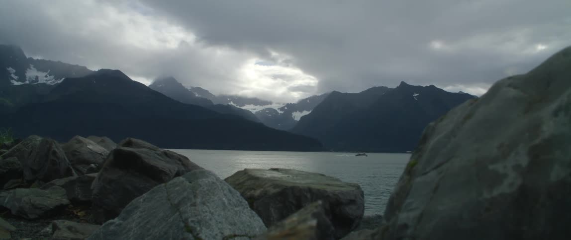 Boat sailing on the calm surface of a lake in the mountains at evening