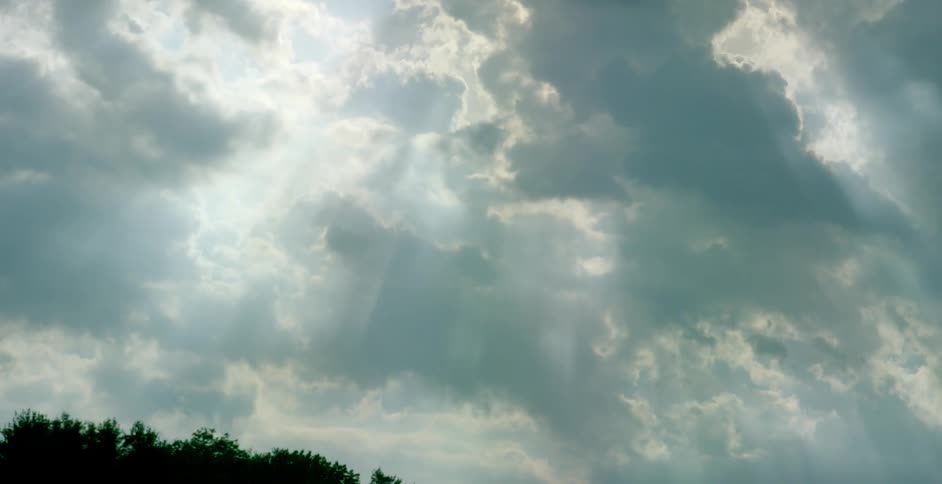 Sun rays shine down between moving clouds