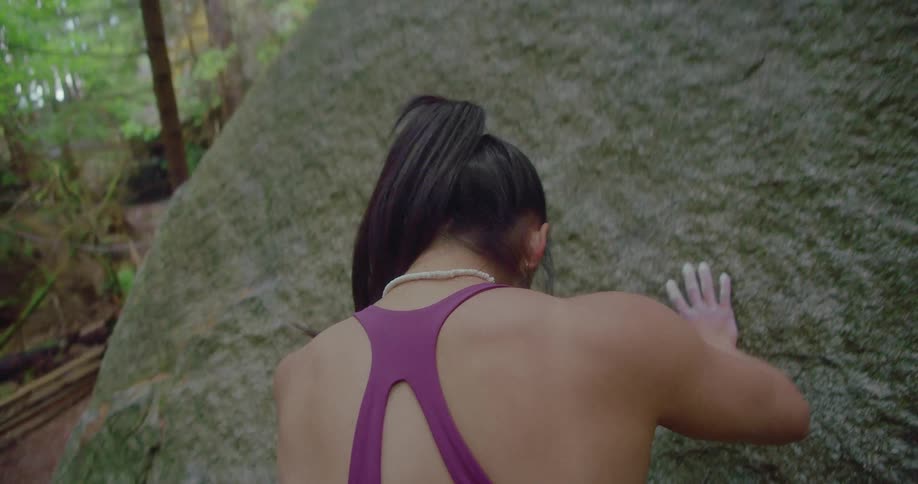 A woman climbs up a mountain while being filmed from the back