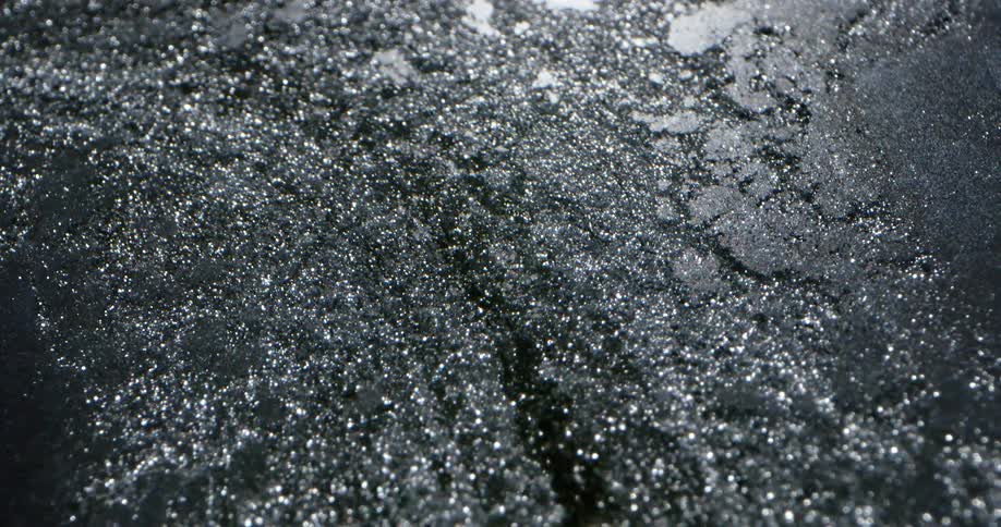 Close up of the shimmering surface of a dark flowing liquid