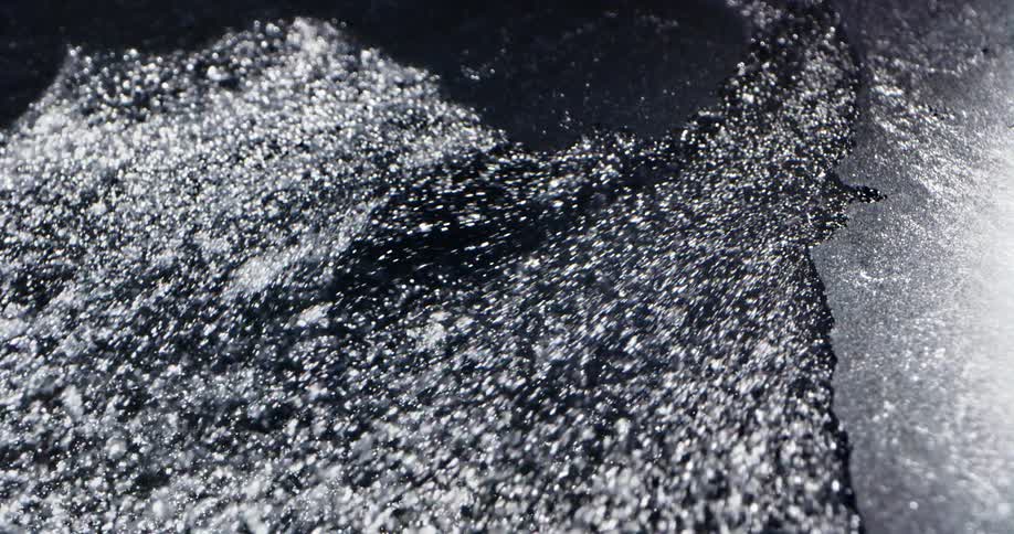 Surface ice cracks and breaks apart as shimmering water flows