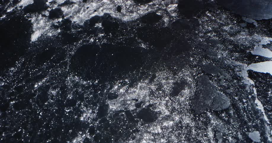 Sparkling melt water pulls pieces from dark ice sheet