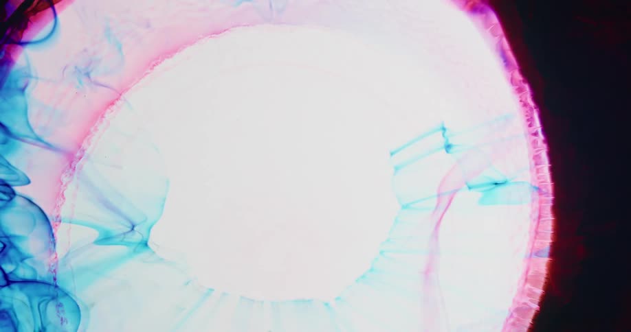Expanding circle of bright white ink creates ripples on dark red liquid ink