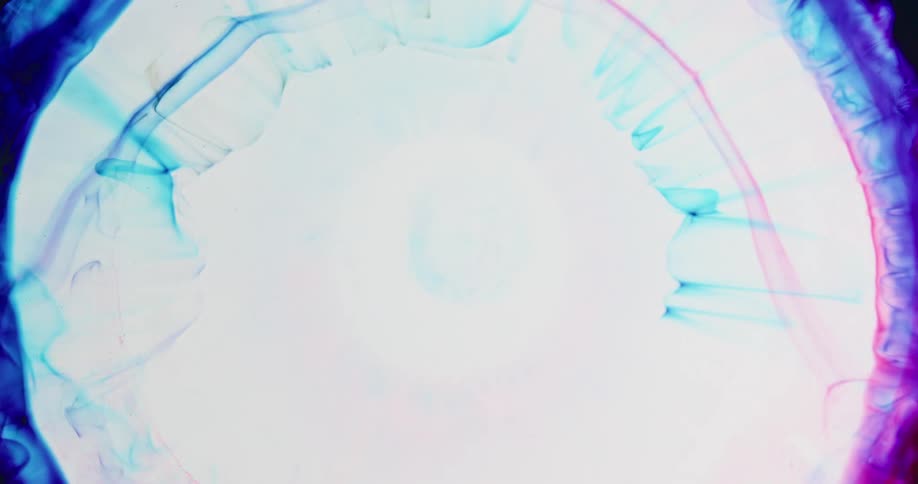 An explosion of white moves across red and blue colors in the darkness and shrinks back down blending into the white