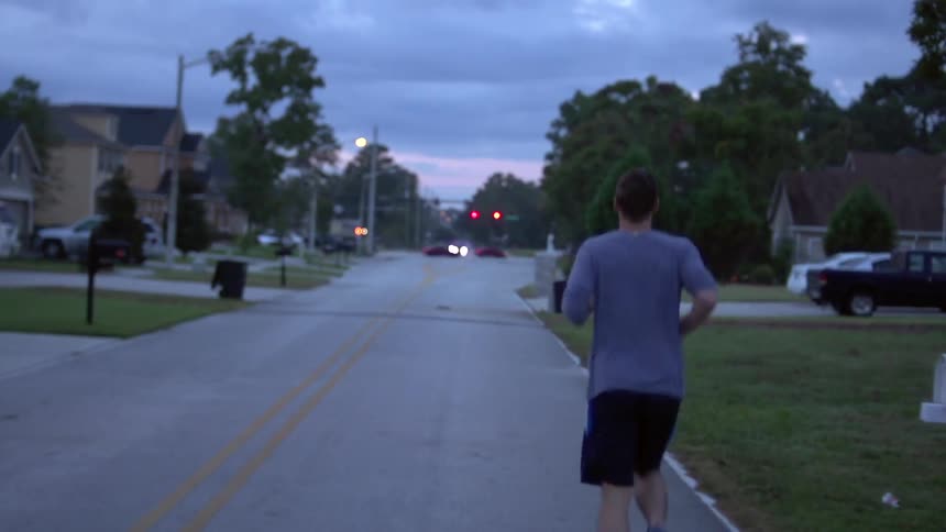 A man jogs on a suburban street early in the evening