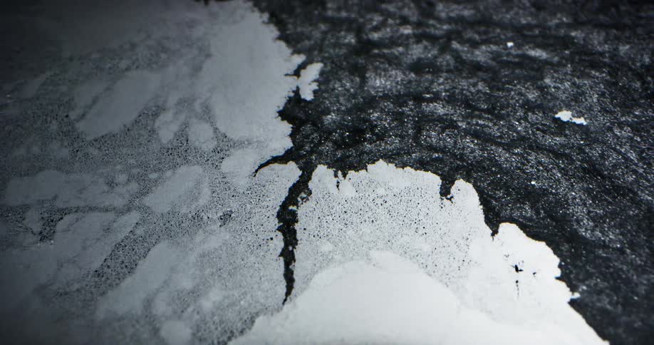 Dark flow of dark gray particles breaks white sheet apart