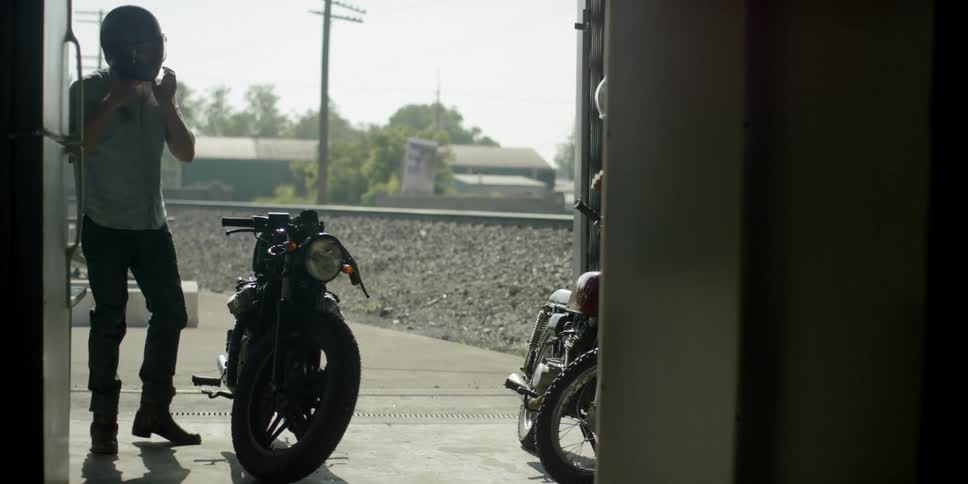 A man gets off his motorcycle and takes off his helmet