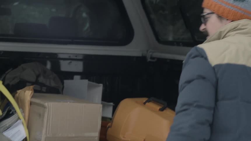A man throws a box into his vehicle and then closes the door