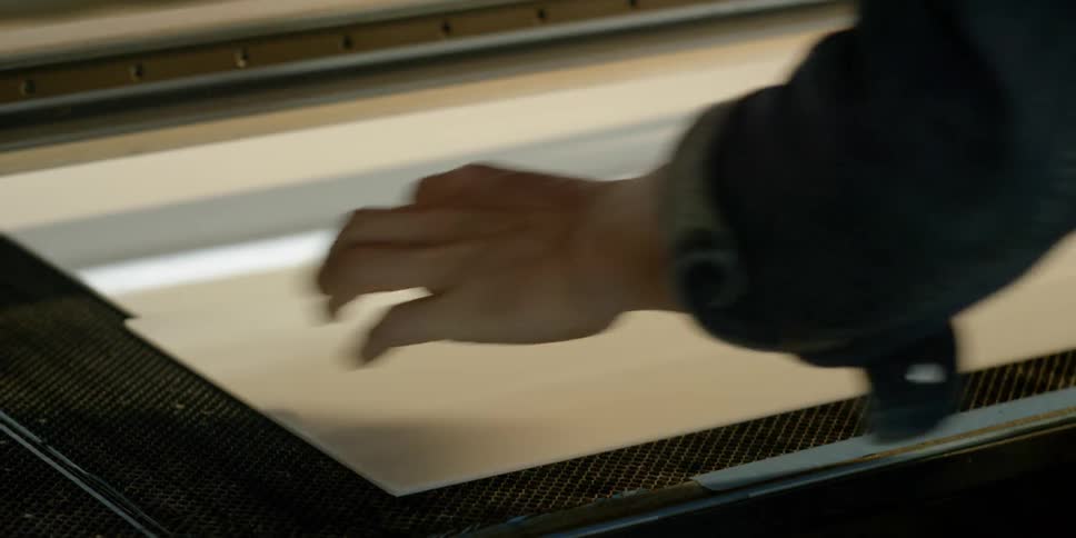 A man places a white sheet of vinyl on a machine
