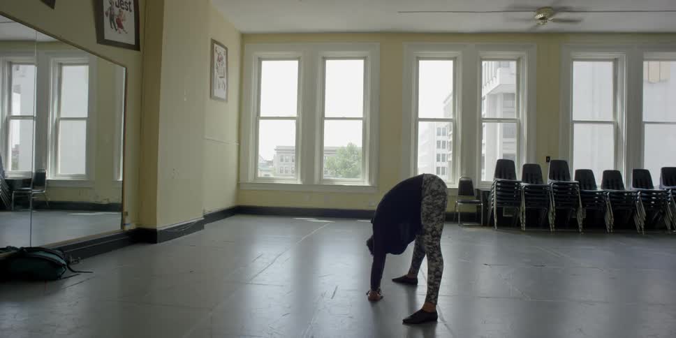 A woman stretches in front of a mirror