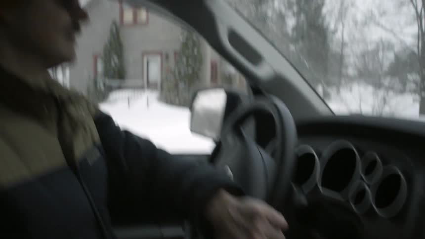 A man in a heavy coat driving a car on a snowy winter day