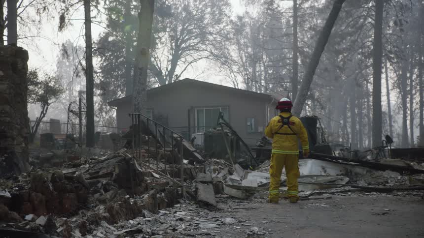 A fireman walks through debris and rubble after a house fire