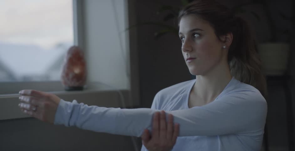 A young woman stretches her arms at home