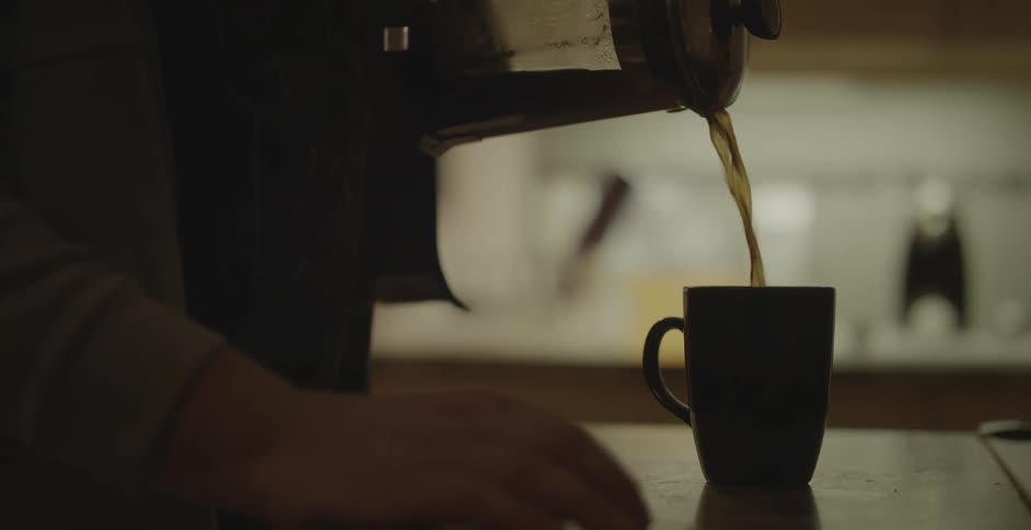 Person pours coffee into a mug then picks mug up