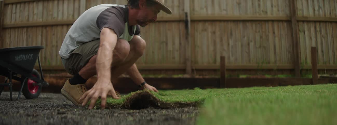 A white man is doing yard work outside in his back yard