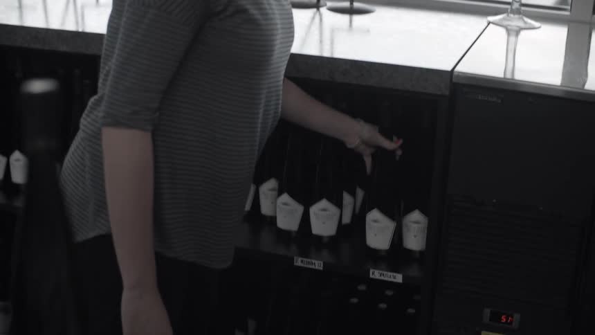 A woman puts away a bottle of wine