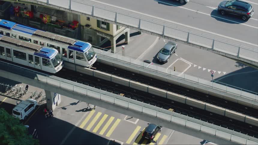 Trains travel along a bridge over an intersection in a city during the day