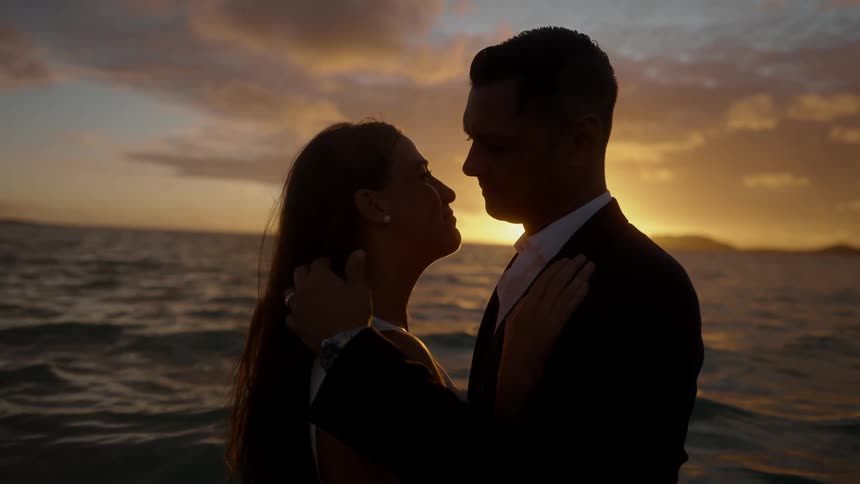 The bride and groom hold each other in the ocean