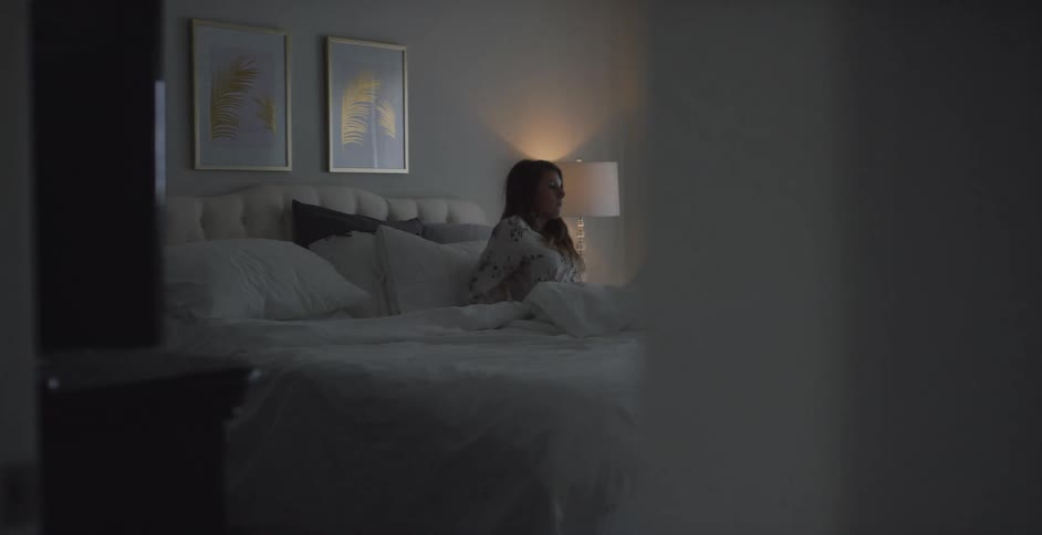 A woman is sitting in her bedroom during the morning