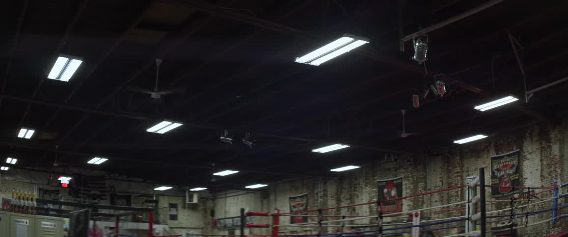 Lights turn on in an empty room with a boxing ring