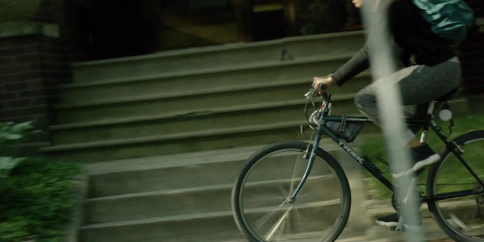 A woman rides a bike on sidewalks in a suburban neighborhood