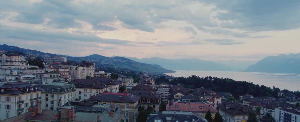 Town sitting on shore stretches to foggy mountains on the horizon