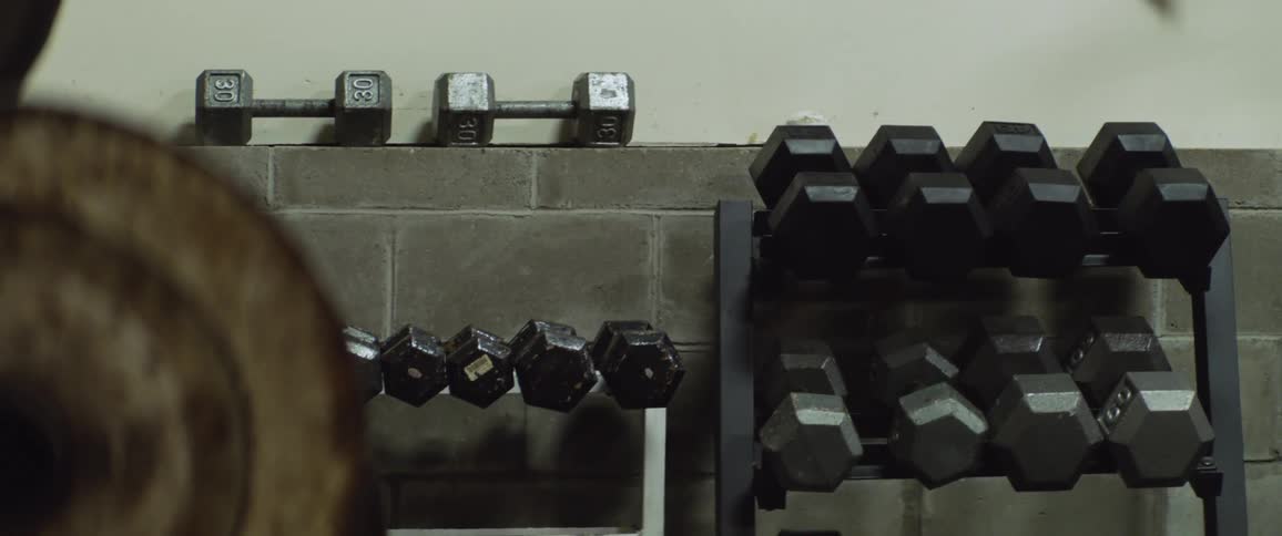 Someone is inside of a gym and can see the weights on the shelf