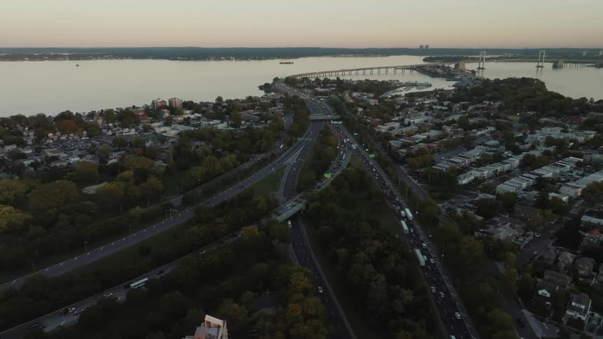 Dense traffic travels along a freeway in a city in the evening