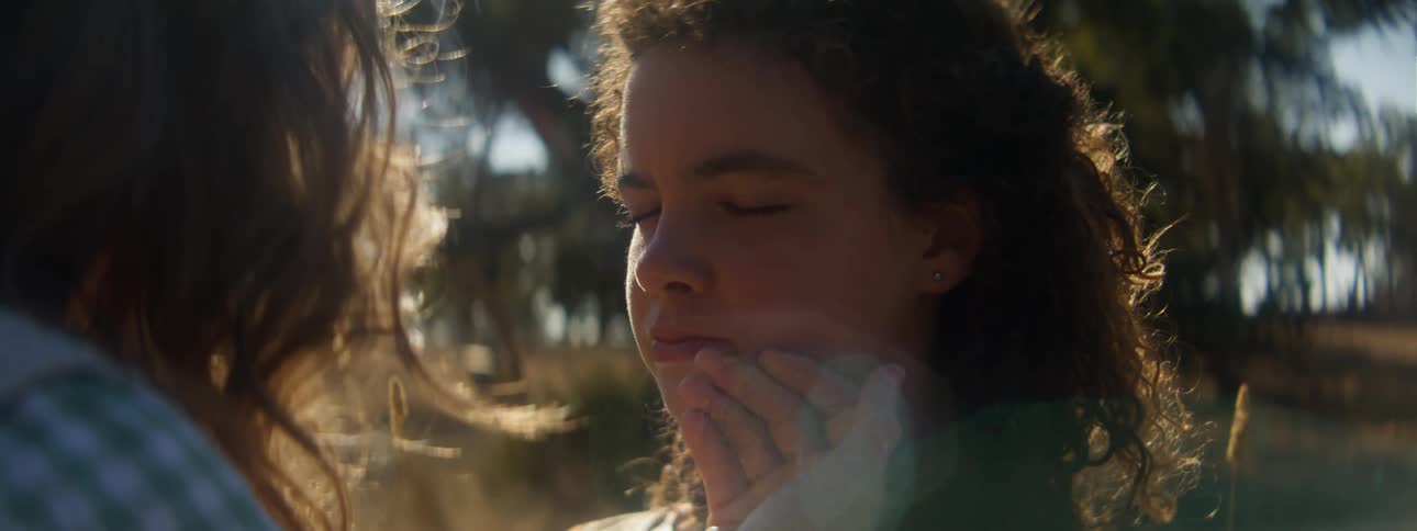 A woman touches a girls face outside