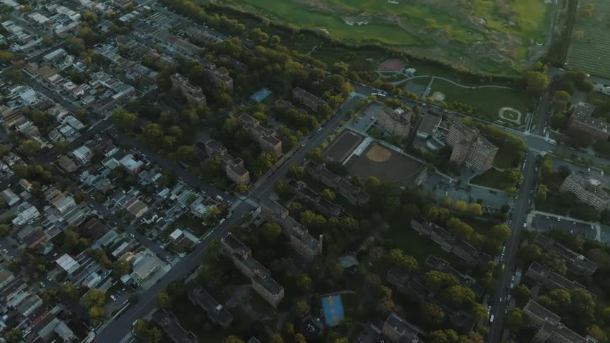 Aerial view of a city along the coast as traffic moves on the neighborhood streets and a bridge stretches across the water