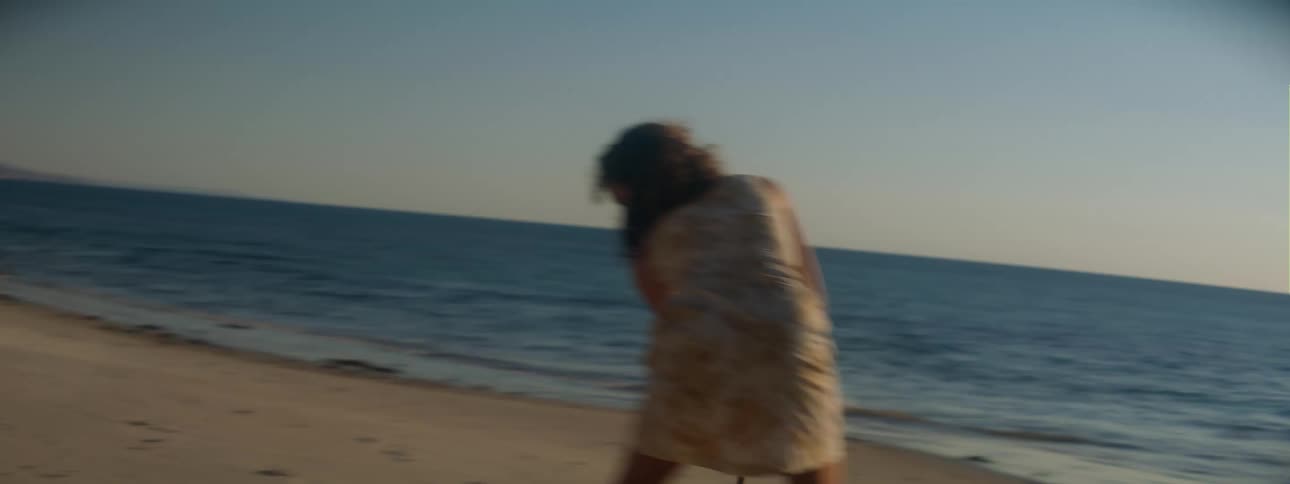 A girl swings a stick on the beach