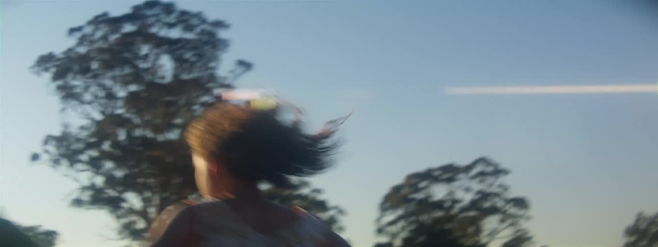 Woman runs and skips across pasture on sunny day
