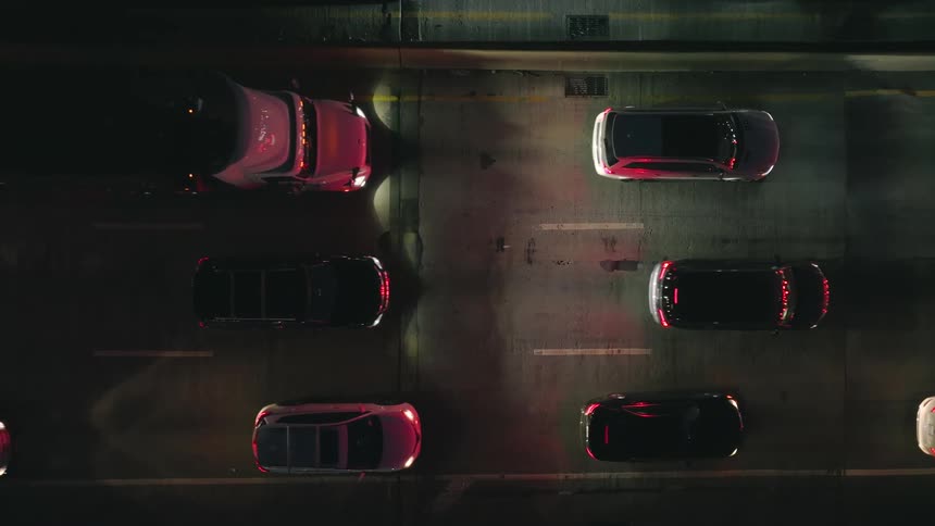 Cars and trucks are moving slowly on a road at night with their headlights on