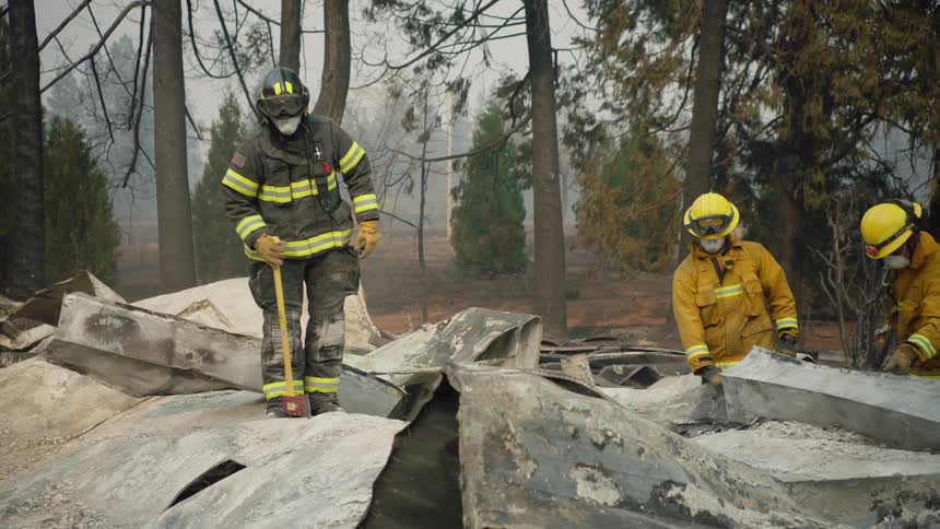 Firefighters dig through debris of a fire