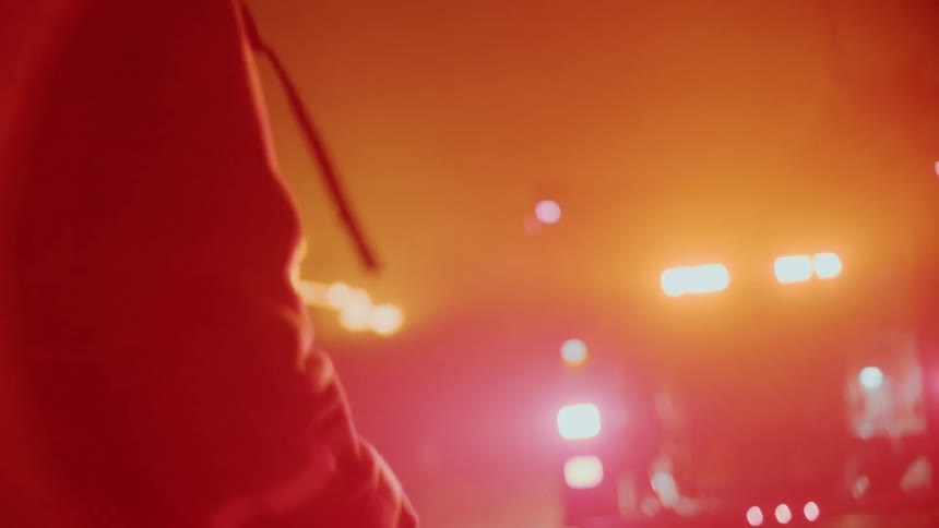 An emergency response crew is standing outside as the red lights from their truck fill the smoky air