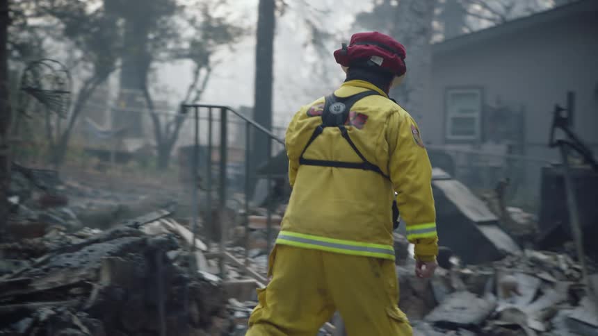 There is a fire fighter that is walking around after a storm