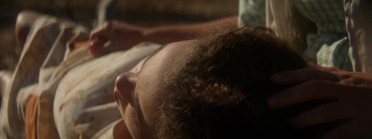 A person is brushing a resting girls hair