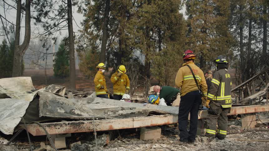 A group of firefighters and rescue people gathered around rubble and debris
