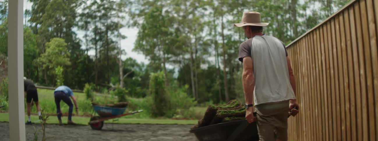 A man is pushing a wheelbarrow in the yard